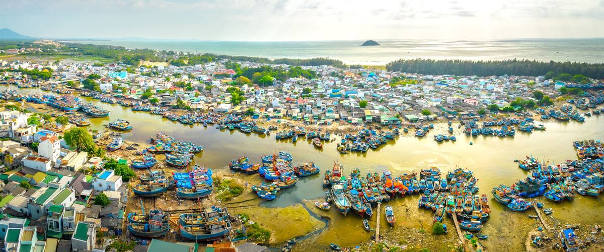 A coastal town with numerous boats docked along the shore and a dense cluster of buildings.