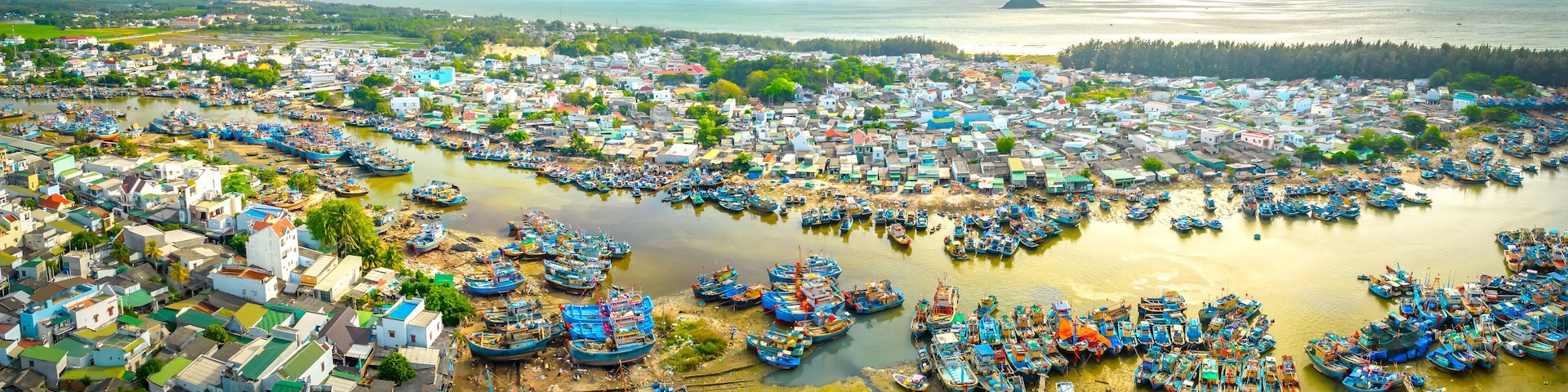 A coastal town with numerous boats docked along the shore and a dense cluster of buildings.
