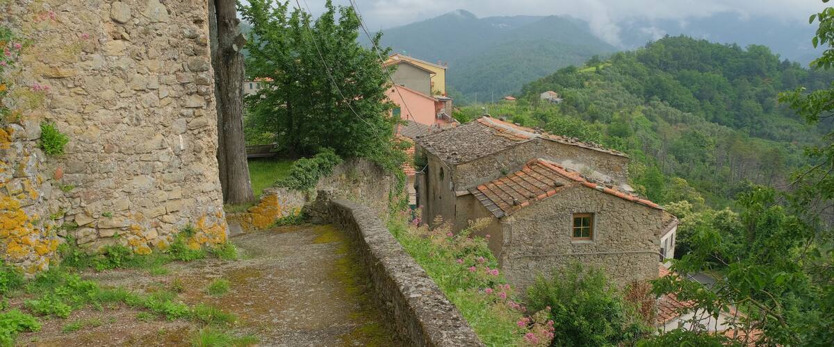 A stone wall, a narrow path, and a hillside with buildings.