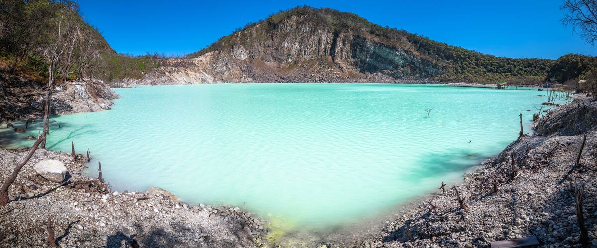 A turquoise lake surrounded by rocky terrain and a forested mountain.