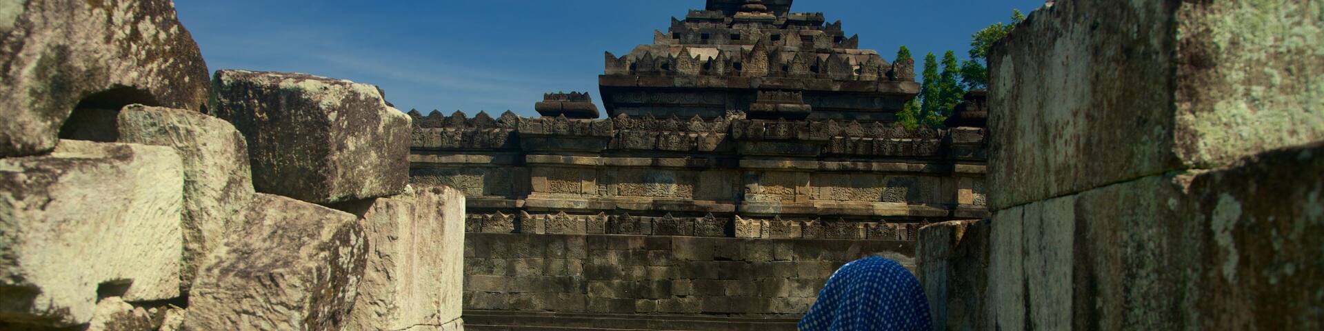 A temple with intricate carvings and a central tower, viewed through a stone archway.