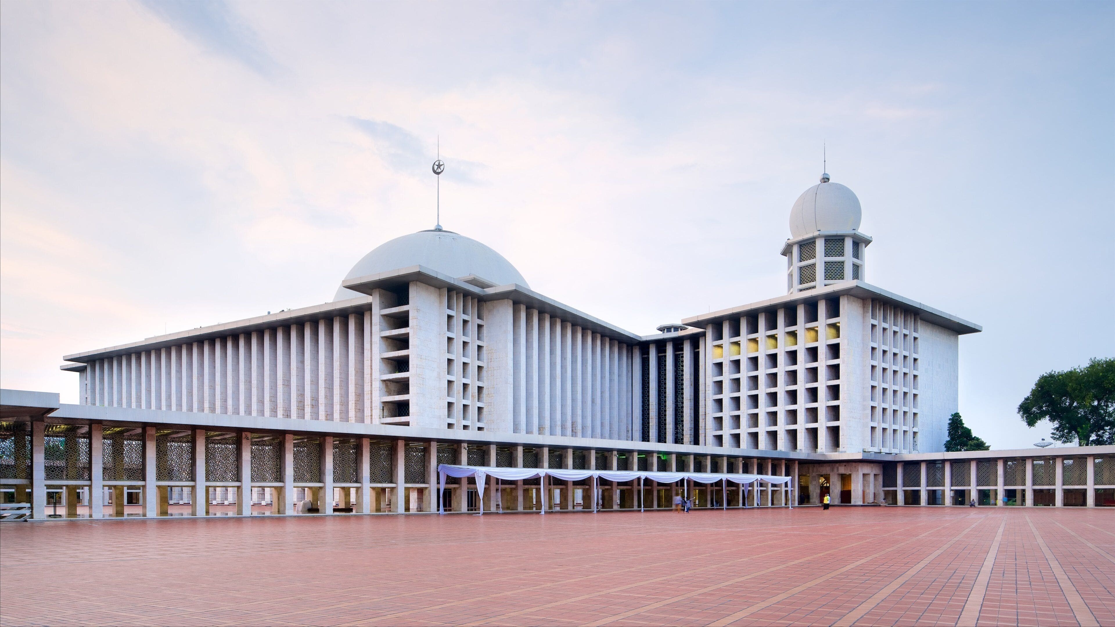 A large, modern building with two domes and a spacious courtyard.