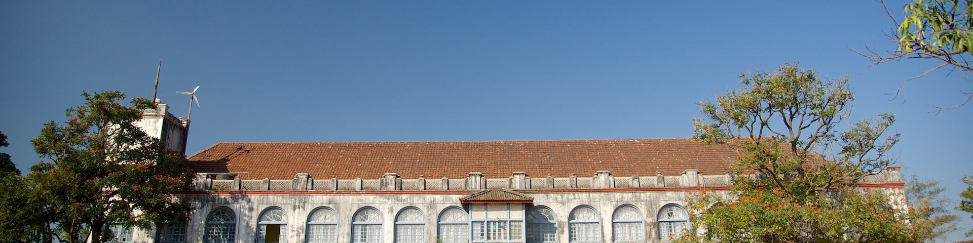 A large, historic building with a tiled roof and multiple arched windows.