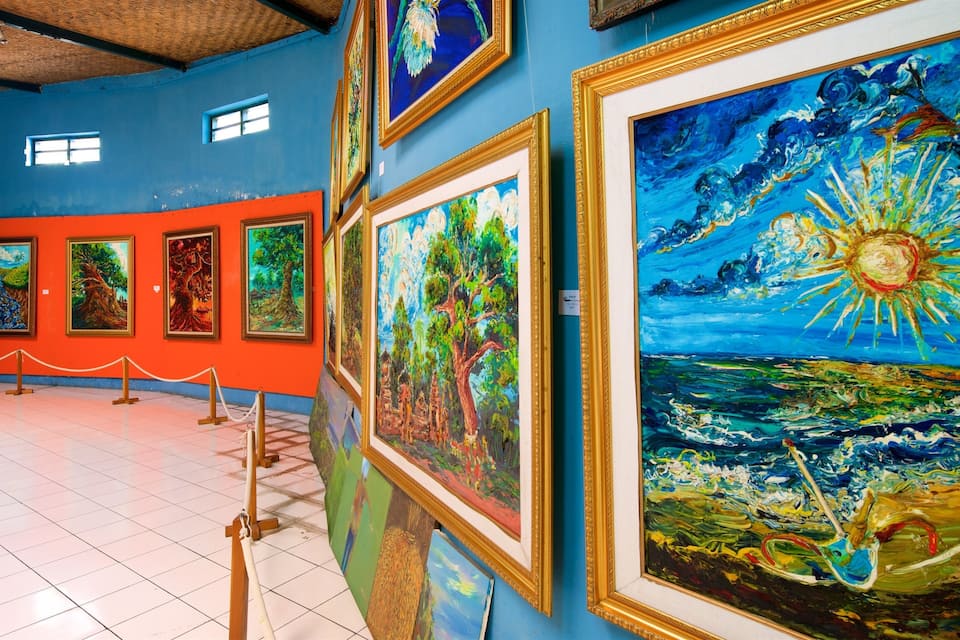 Una galeria amb pintures vibrants, incloent una escena de sol i oceà, i una sèrie de paisatges.