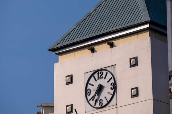 A vintage clock adorning the wall of a building with a classic green roof.