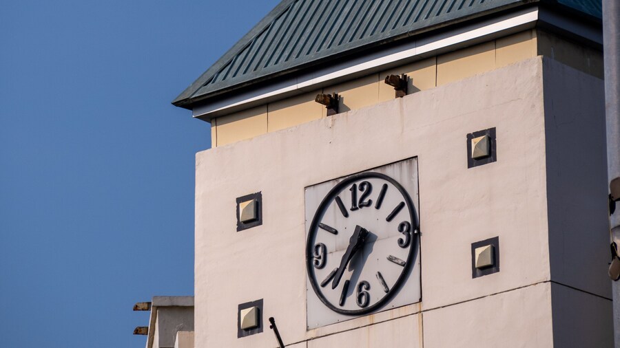 A vintage clock adorning the wall of a building with a classic green roof.