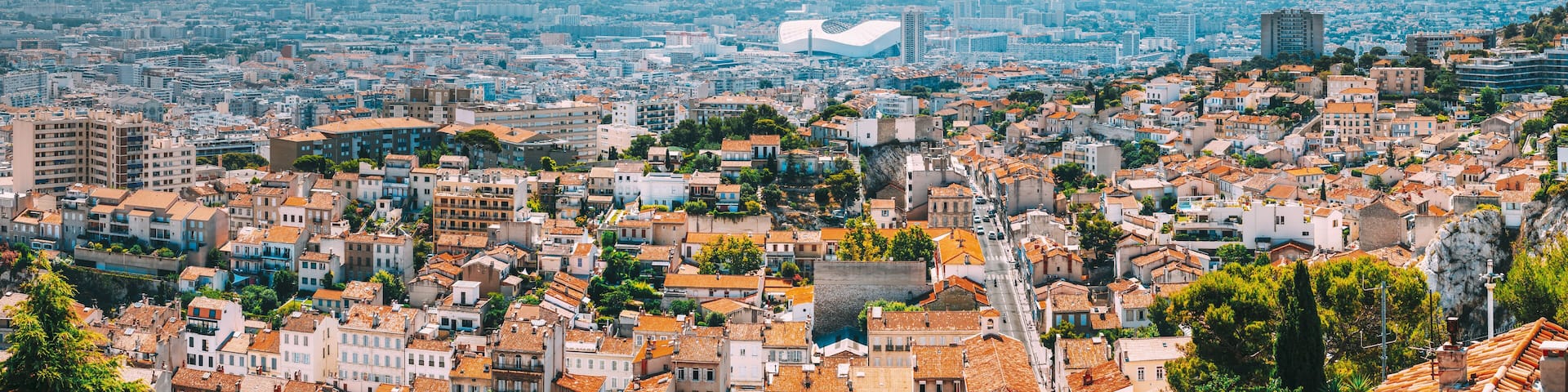A cityscape with a prominent modern building and a mountain range in the background.