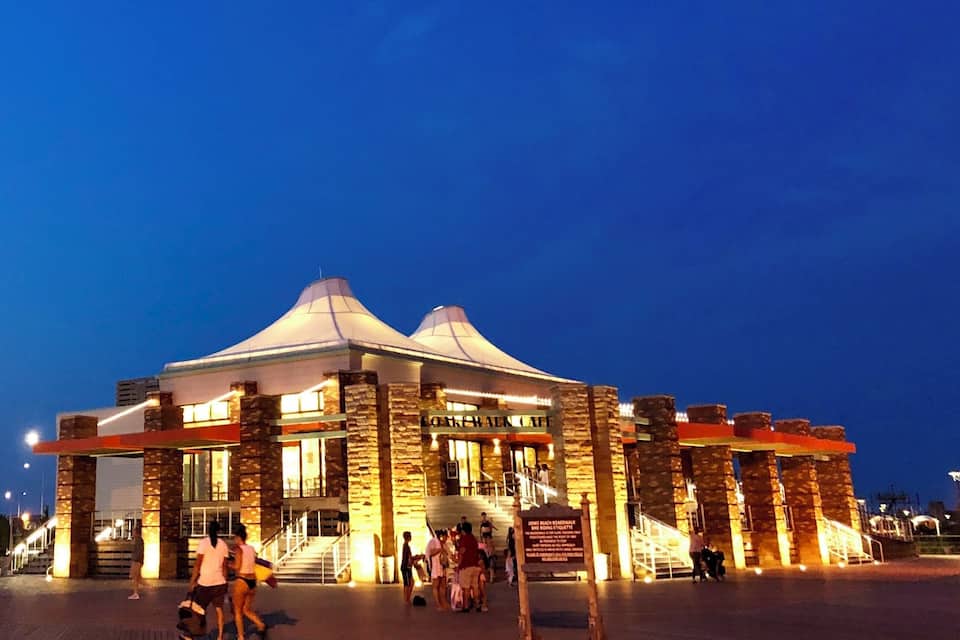 A large, illuminated building with a sign reading "Coachman Cafe" and a signboard indicating "Jones Beach Roadside Restroom."