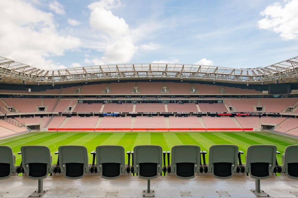 A large, empty stadium with a green field and red seats.