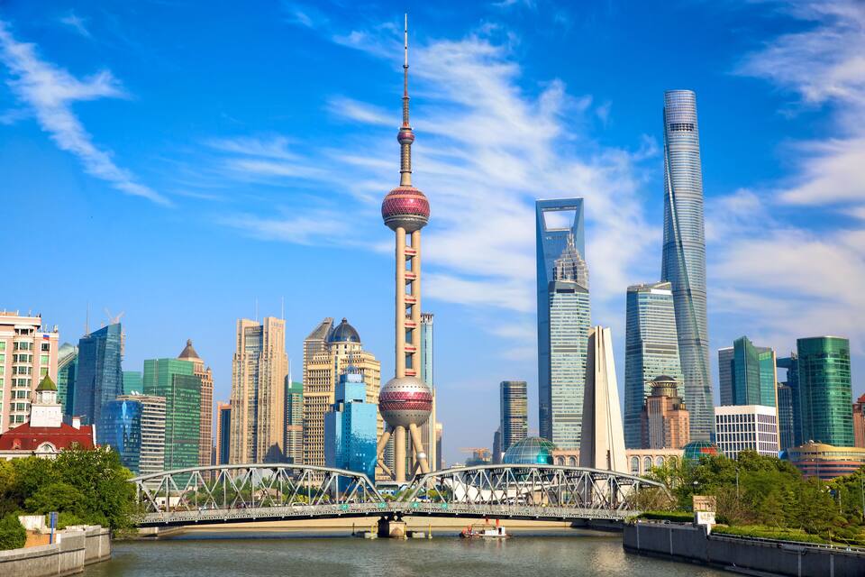 Un horizonte urbano con rascacielos modernos, una torre destacada con un mirador esférico y un puente sobre un río.