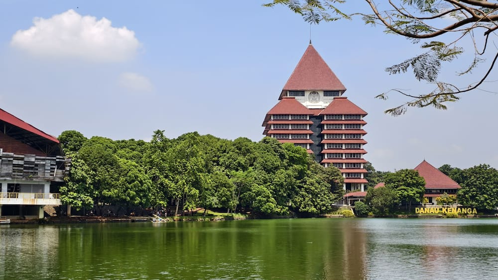 reflection of building on Kenanga Lake. Rectorate Building of the University of Indonesia. with trees, blue sky and clouds