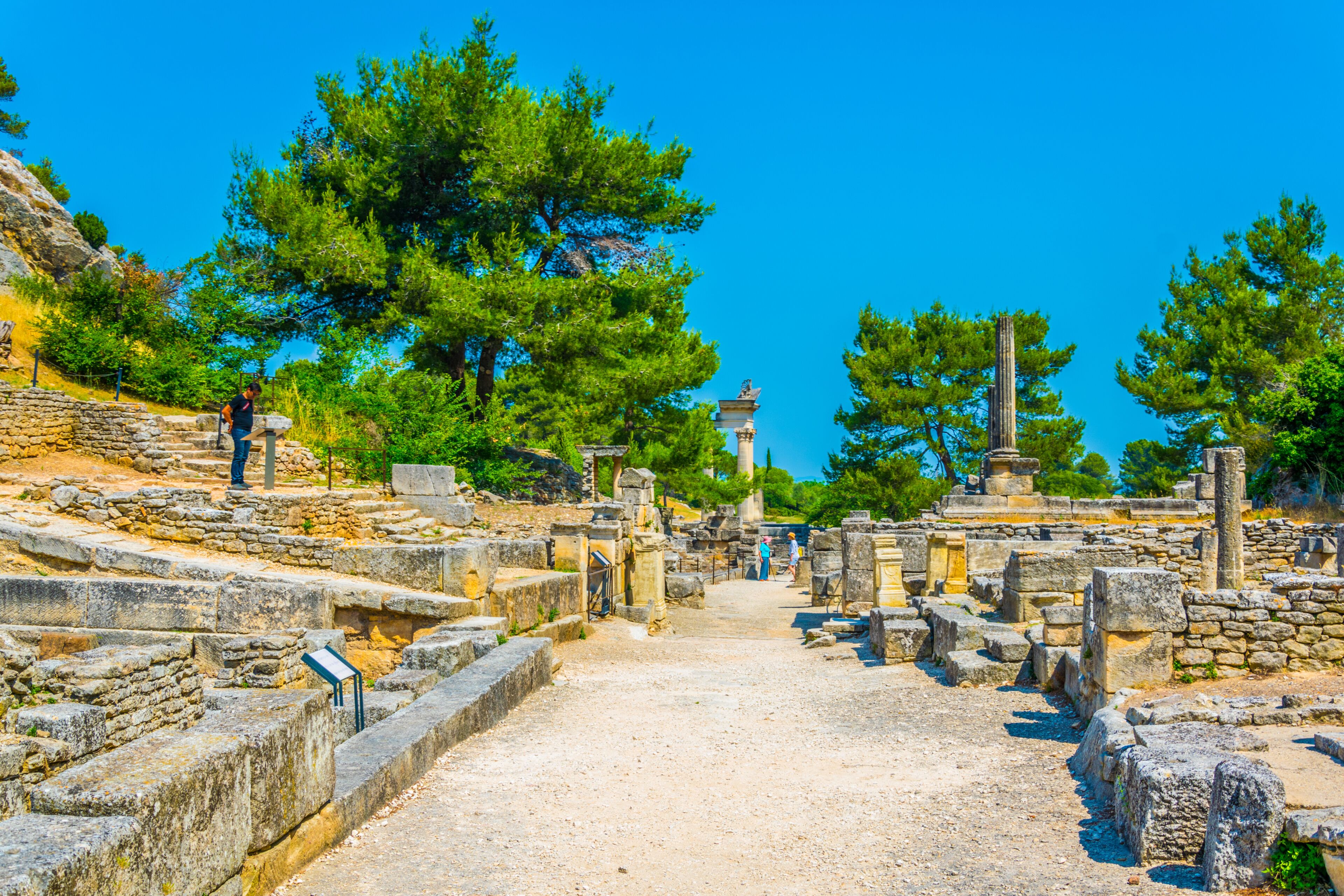 Ancient ruins with stone pathways, columns, and a clear blue sky.