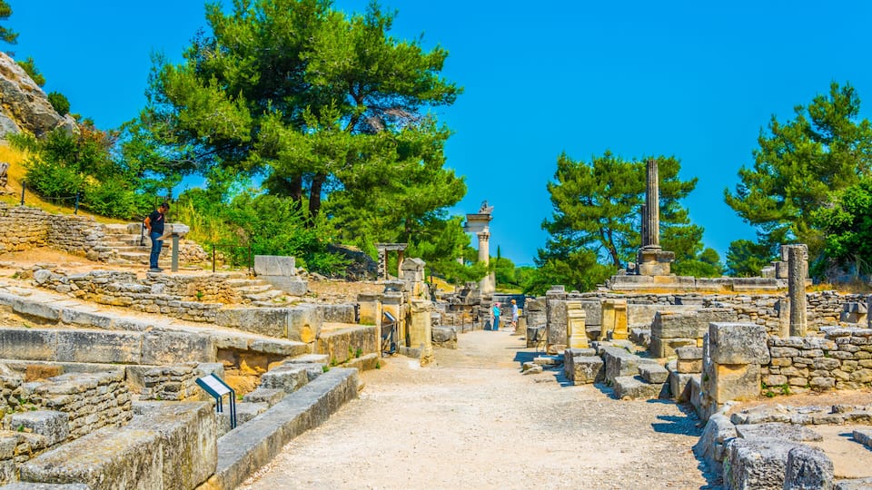 Ancient ruins with stone pathways, columns, and a clear blue sky.