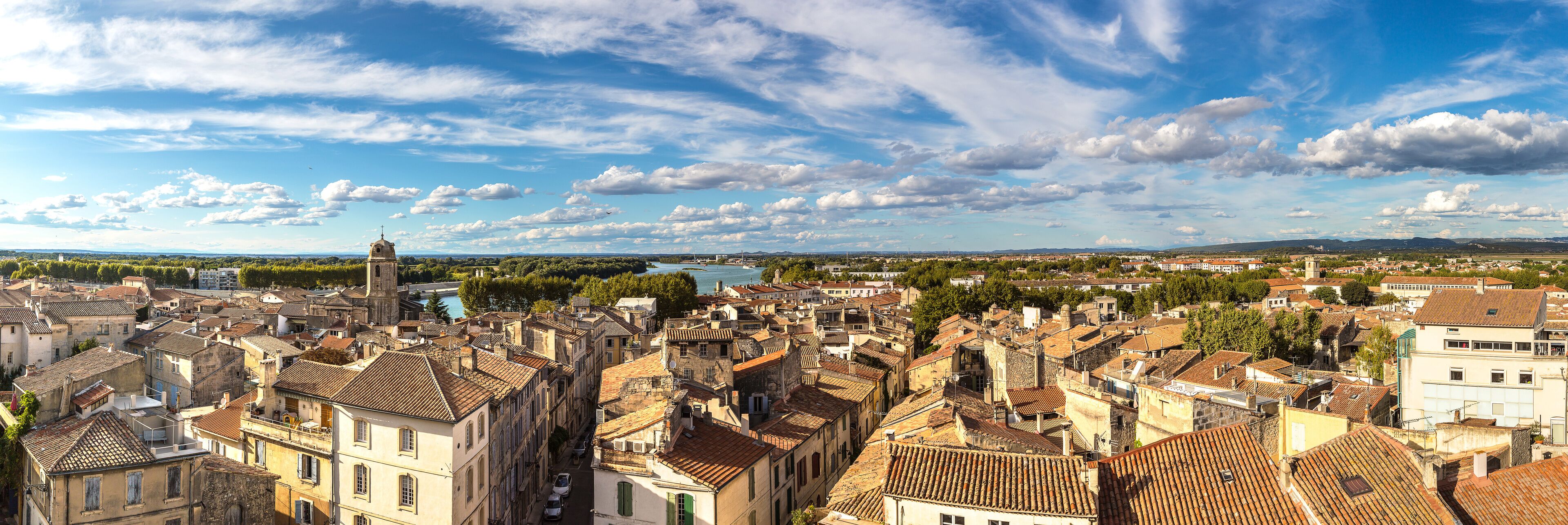 A historic town with a prominent church tower, dense architecture, and a river in the background.