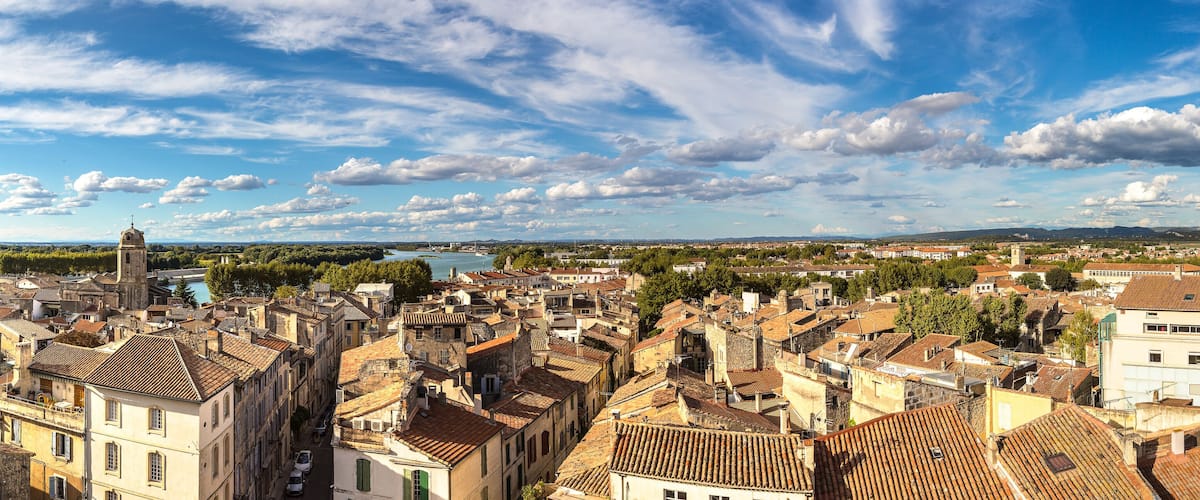 A historic town with a prominent church tower, dense architecture, and a river in the background.
