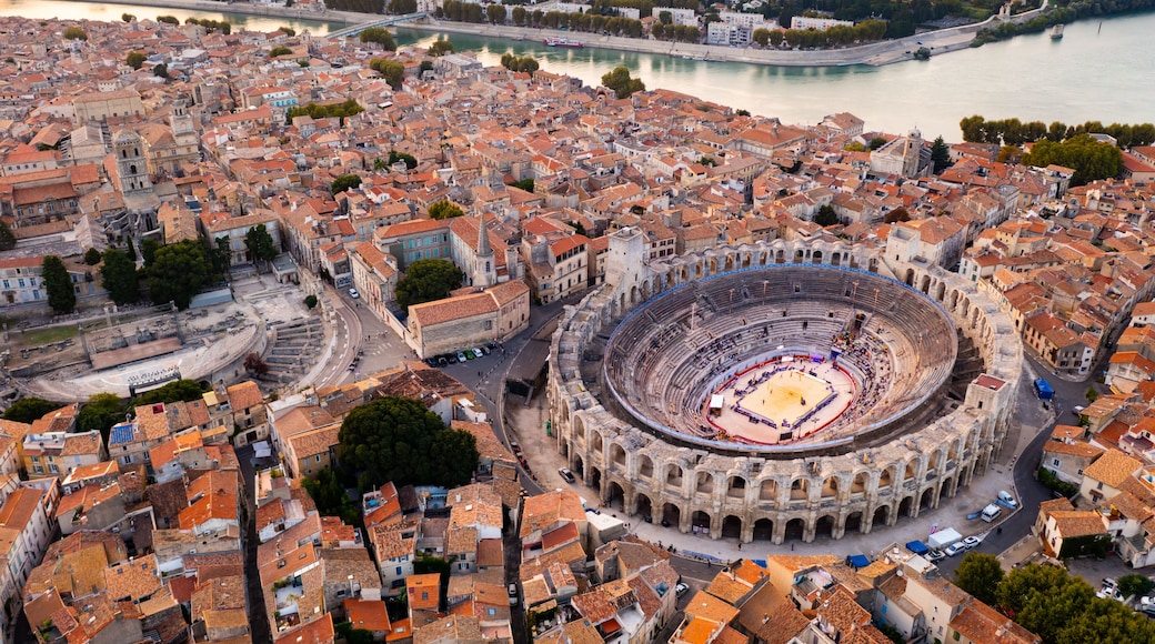 Aerial view of Arles townscape on bank of Rhone river overlooking restored antique Roman amphitheatre and ruins of Gallo-Roman theatre on autumn day, France