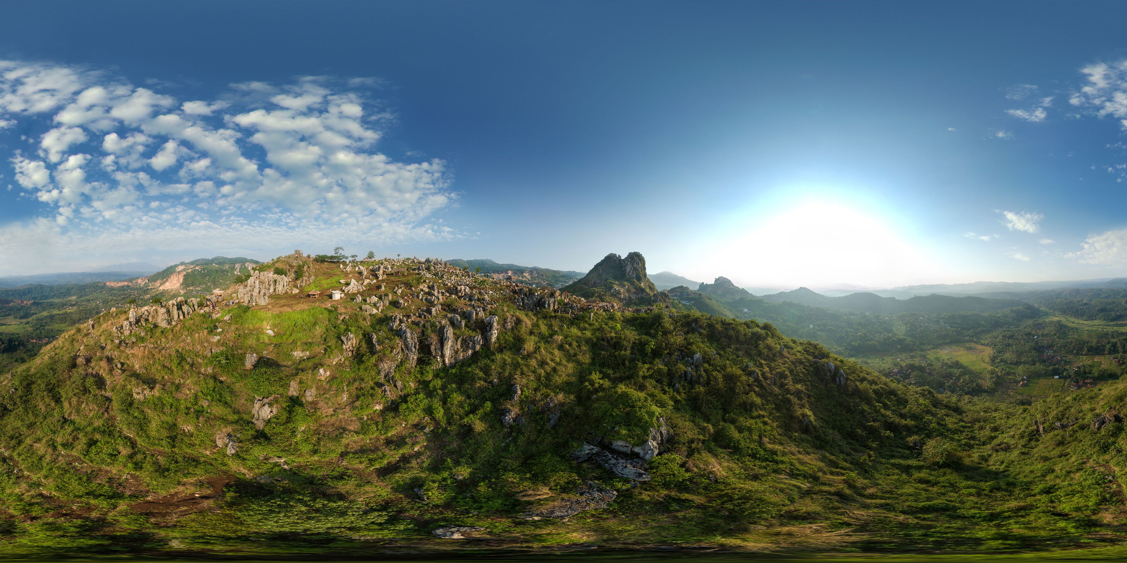 A mountainous landscape with a prominent peak, lush greenery, and scattered buildings.