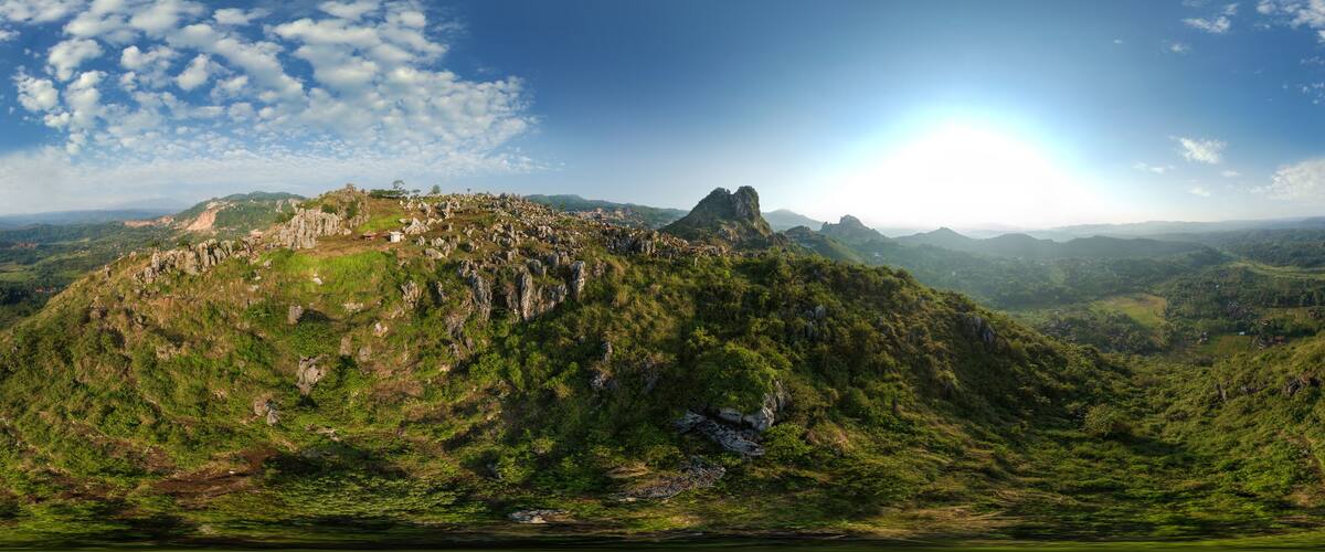 A mountainous landscape with a prominent peak, lush greenery, and scattered buildings.