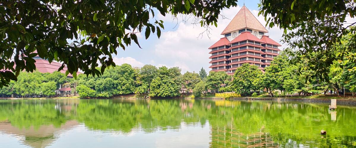 A lake with a reflection of a building and trees.