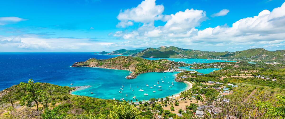 A coastal landscape with turquoise waters, boats, and greenery.