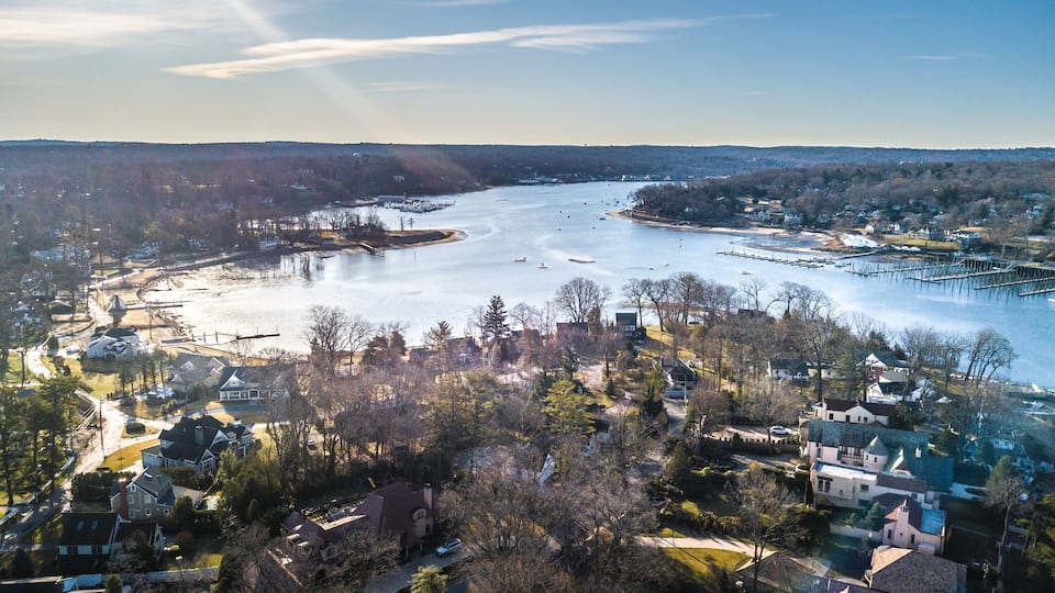 A river with boats, a marina, and residential areas with houses and trees.