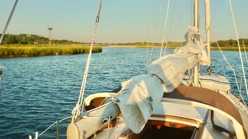 A sailboat heading out of Mattituck Inlet in the early morning light. Long Island, NY. Copy space.
