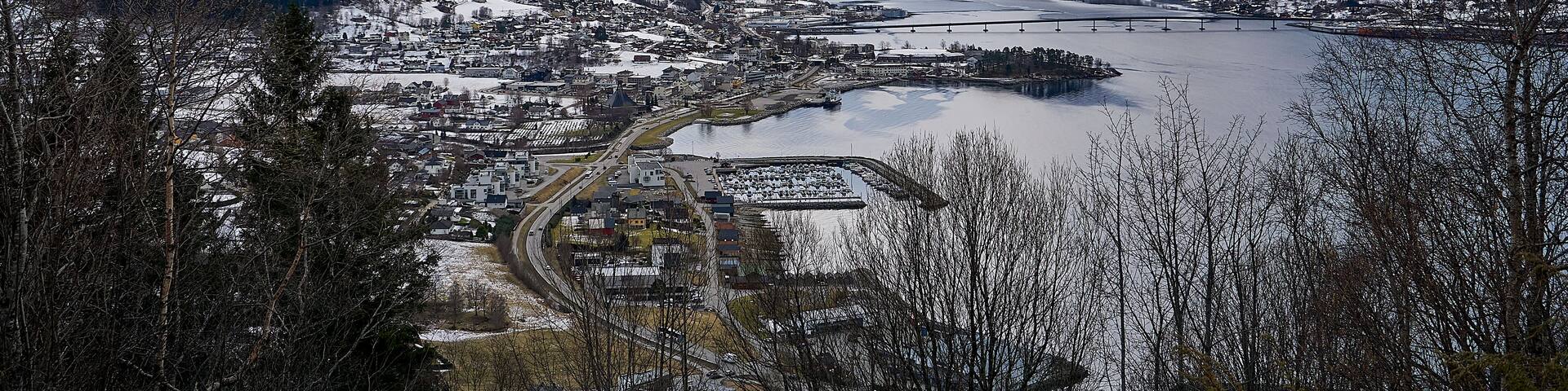 A snow-covered mountainous landscape with a town and a river.
