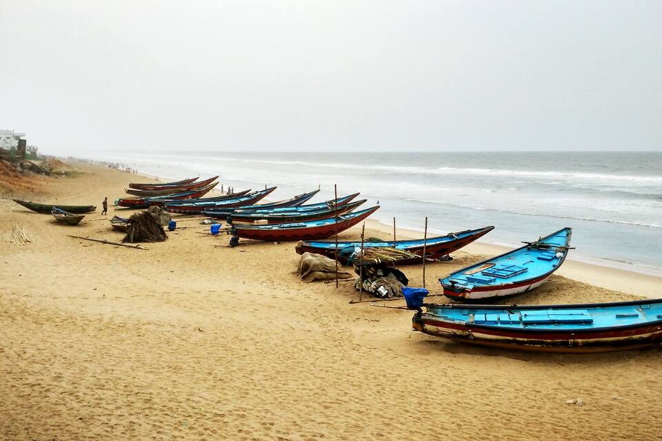 A beach with several boats lined up on the sand.