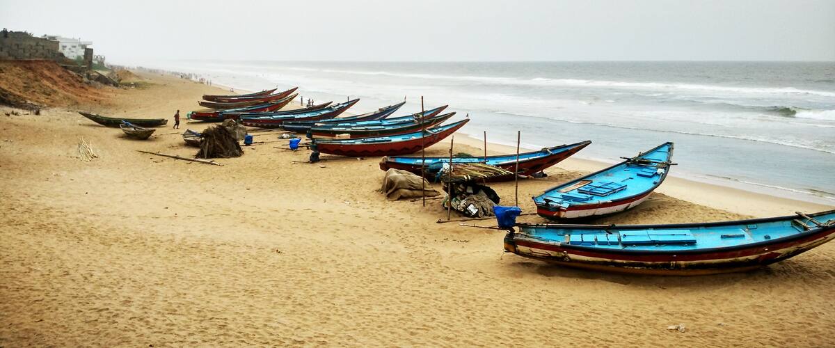 A beach with several boats lined up on the sand.