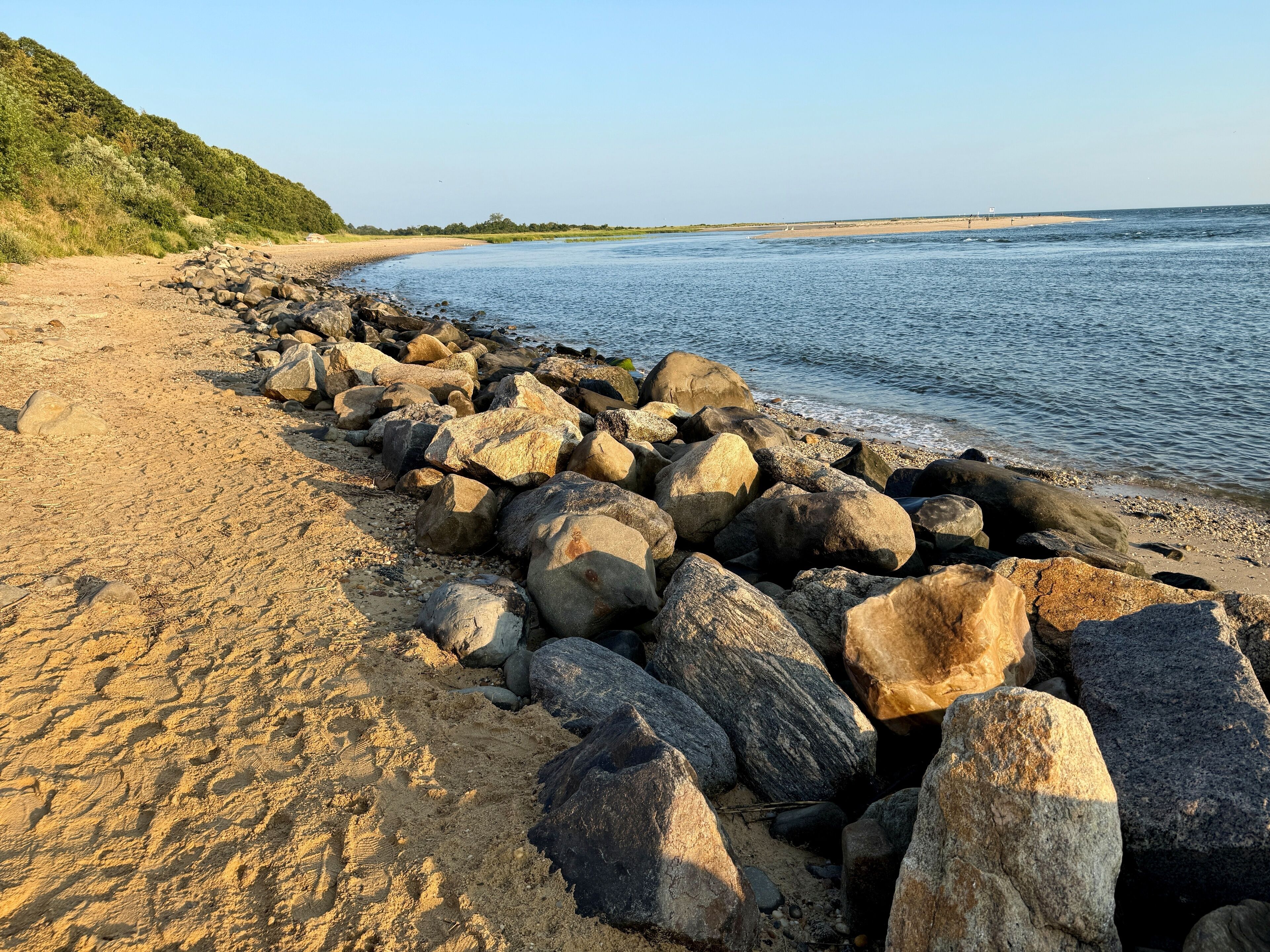 Beautiful golden hour sunrise on the beach at Kings Park Bluffs and Sunken Meadow State Park in Smithtown, NY at dawn. Hot, summer day. Clear, no clouds.  Blue sky, coastline of Long Island Sound.