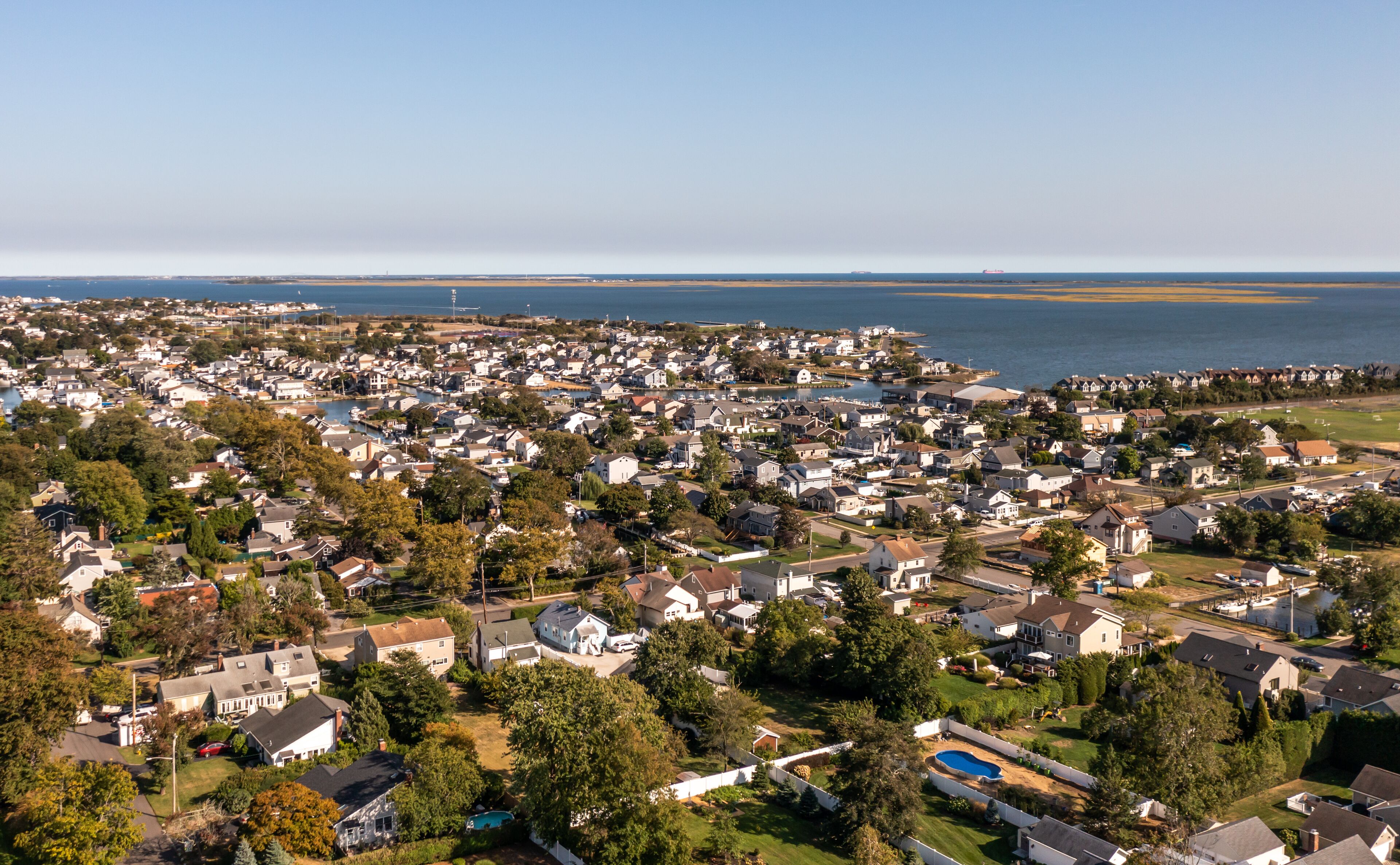 A coastal residential area with houses, a marina, and a large body of water.