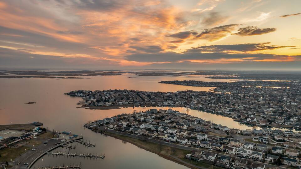 A coastal town at sunset with a marina and residential area.