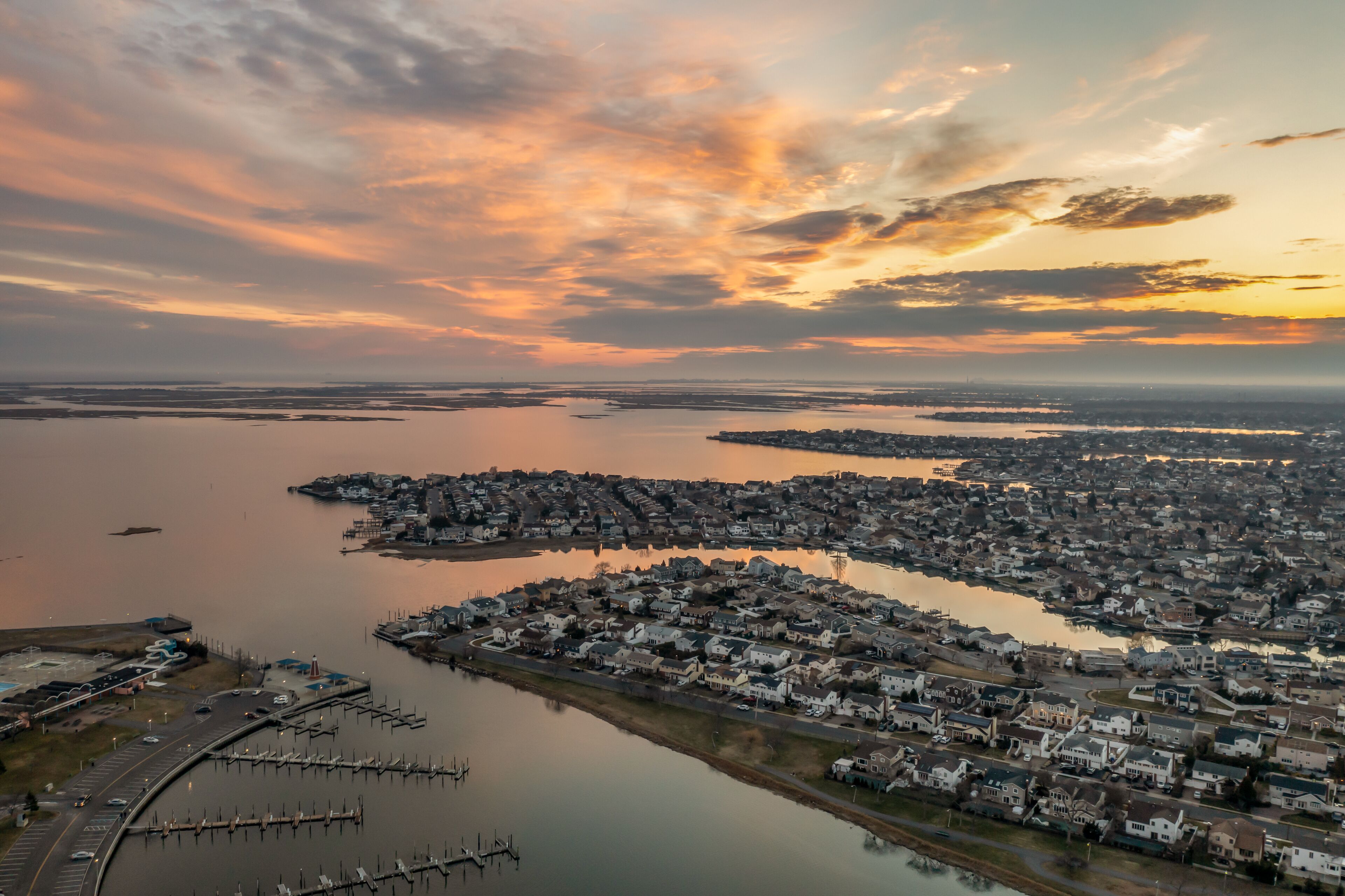 A coastal town at sunset with a marina and residential area.