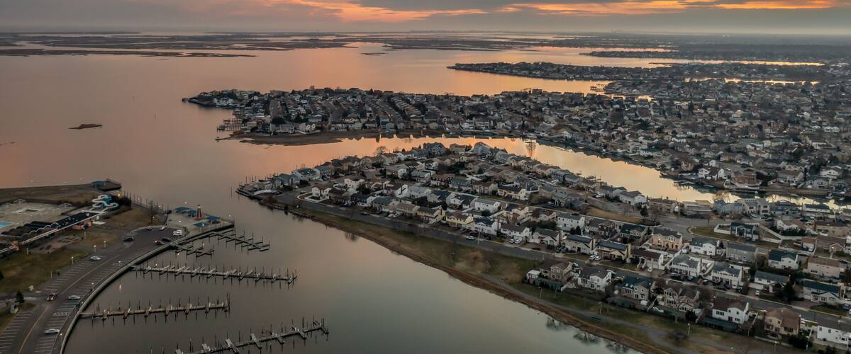 A coastal town at sunset with a marina and residential area.