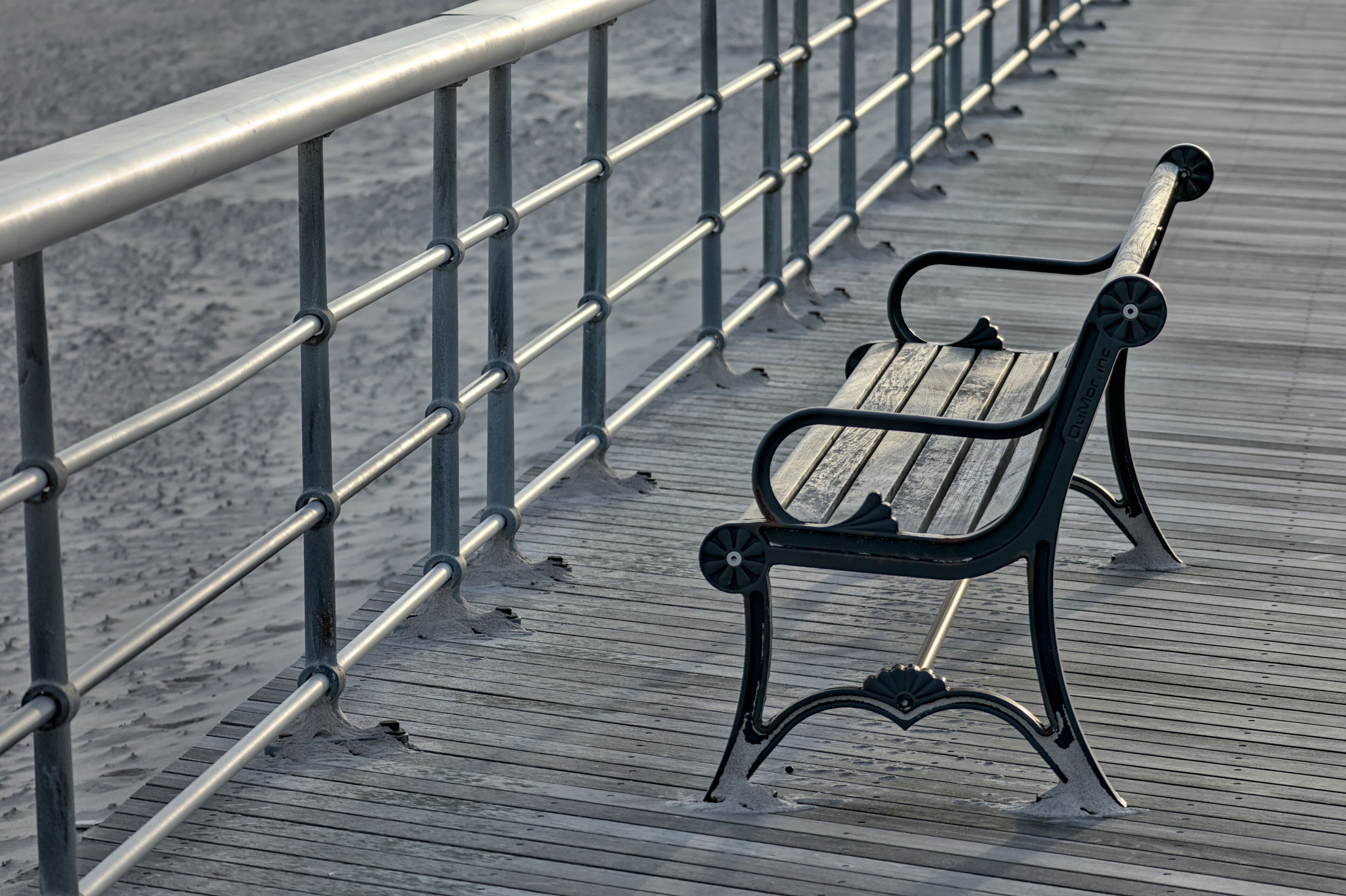 bench on the boardwalk at the beach (jones beach state park on long island nassau county new york) railing with wooden planks and sand (empty, no people) summer relaxation recreation getaway