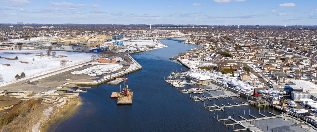 A river flowing through a town with a marina and industrial buildings.