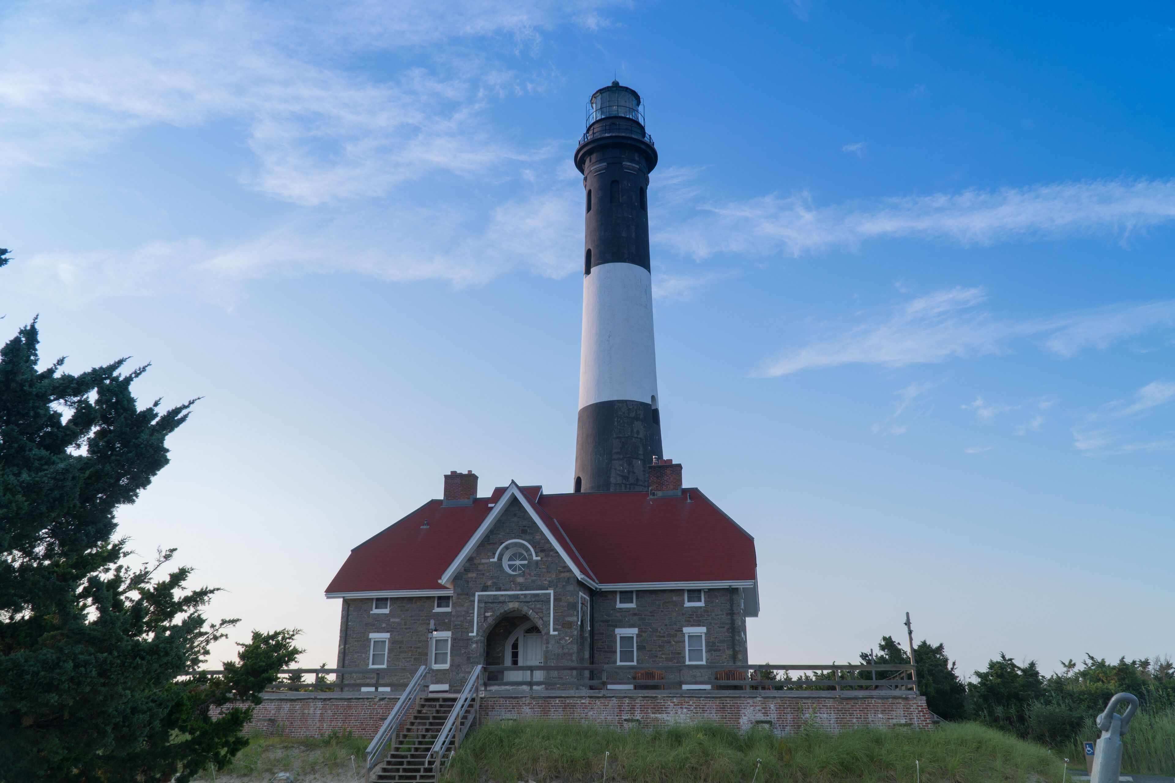Wide establishing shot of generic lighthouse during the day time. Navigation beacon for boats heading to shore
