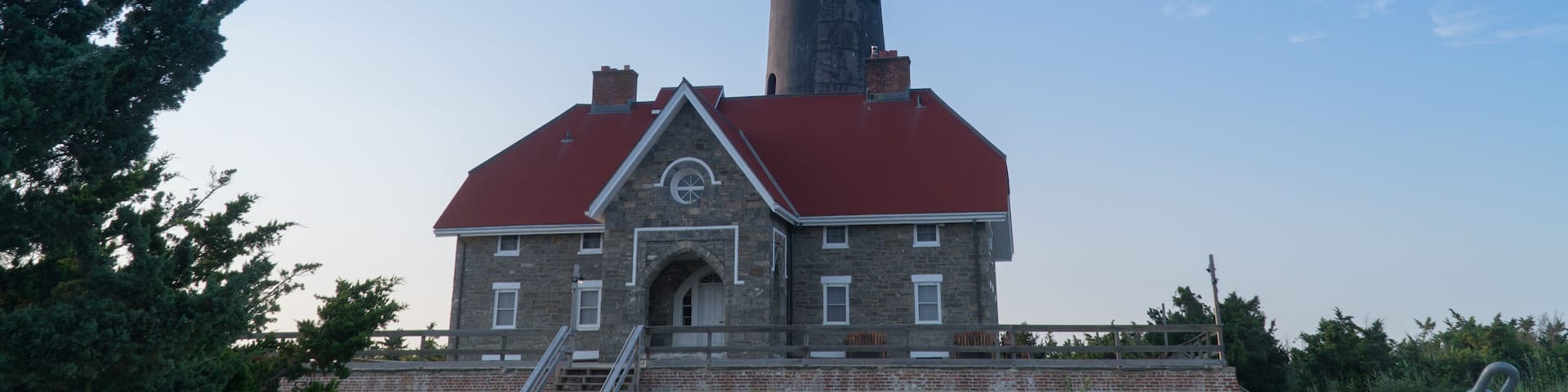Wide establishing shot of generic lighthouse during the day time. Navigation beacon for boats heading to shore