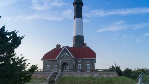 Wide establishing shot of generic lighthouse during the day time. Navigation beacon for boats heading to shore