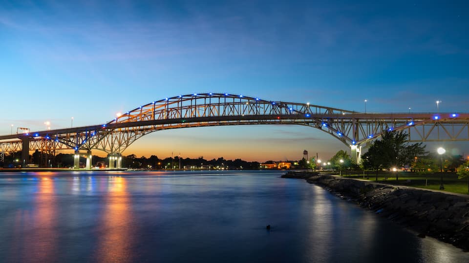 A bridge at dusk with lights reflecting on the water.