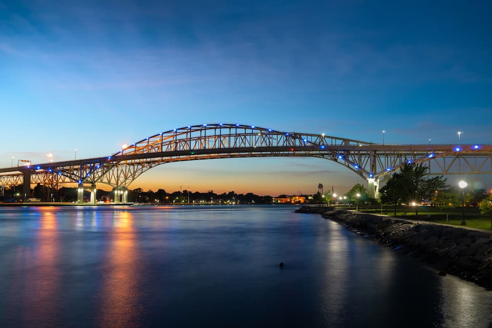 A bridge at dusk with lights reflecting on the water.