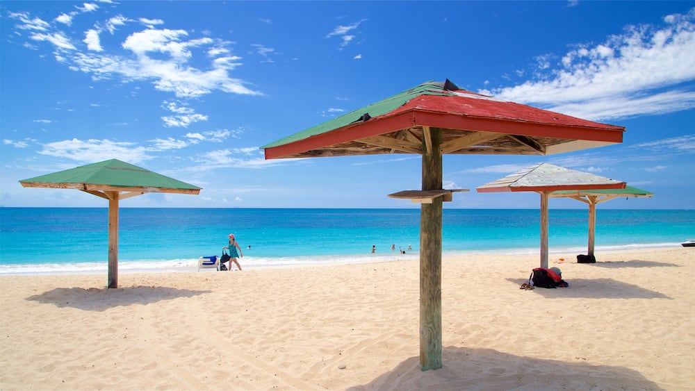 Une plage avec trois parasols en bois et un ciel bleu dégagé.