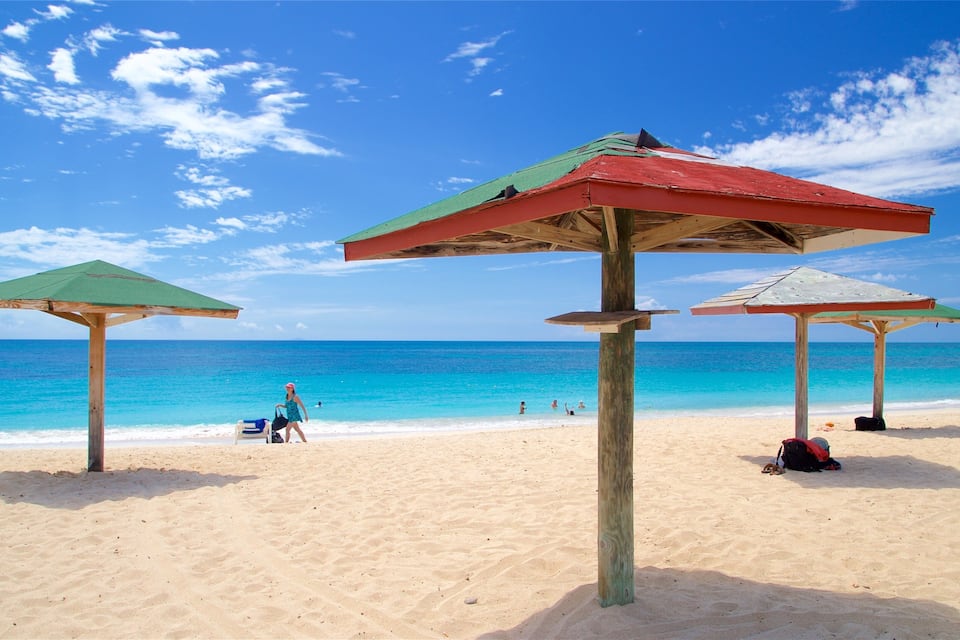 Ein Strand mit drei Holz Sonnenschirmen und blauem Himmel.