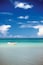 A boat on a clear turquoise sea under a blue sky with scattered clouds.