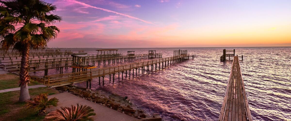 A wooden pier extending into a body of water with a sunset sky.