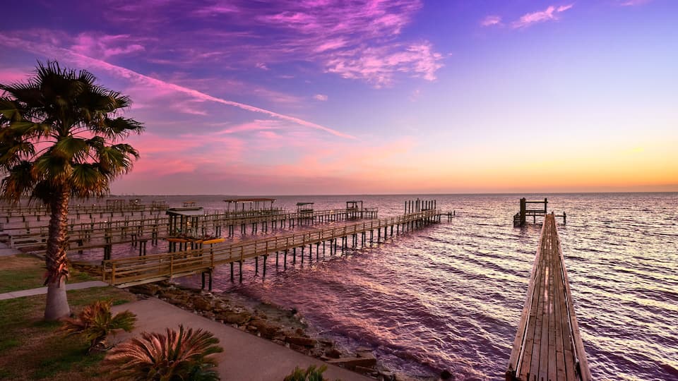 A wooden pier extending into a body of water with a sunset sky.