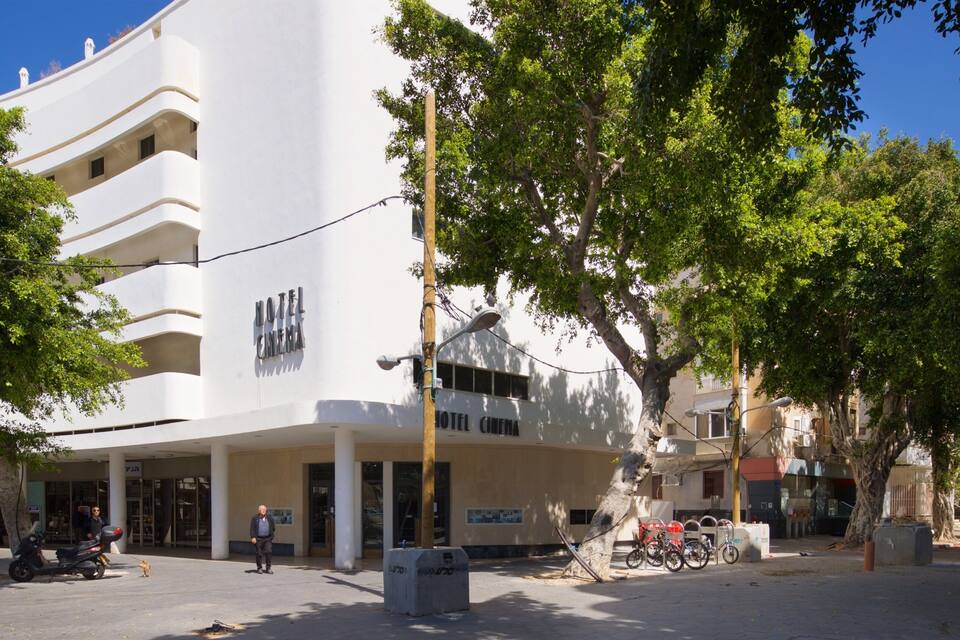 Un edificio blanco con balcones y un cartel que dice "HOTEL CINEMA".