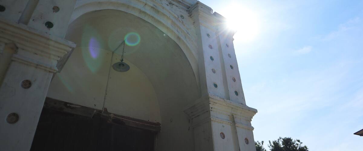 An arched architectural structure with circular windows and a sun shining through it.