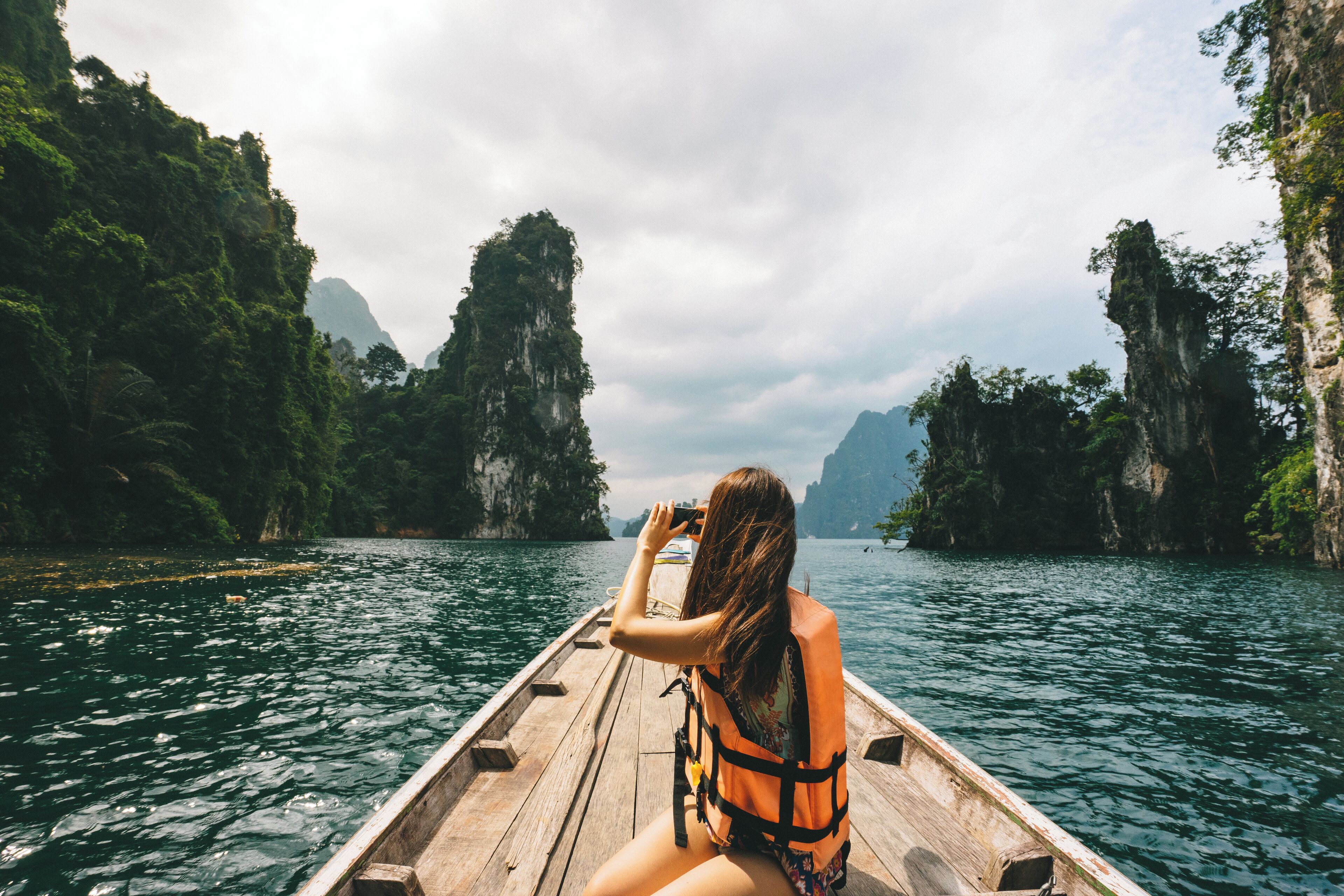 A person in a boat on a river surrounded by cliffs.