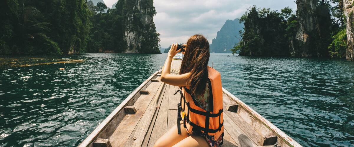 A person in a boat on a river surrounded by cliffs.